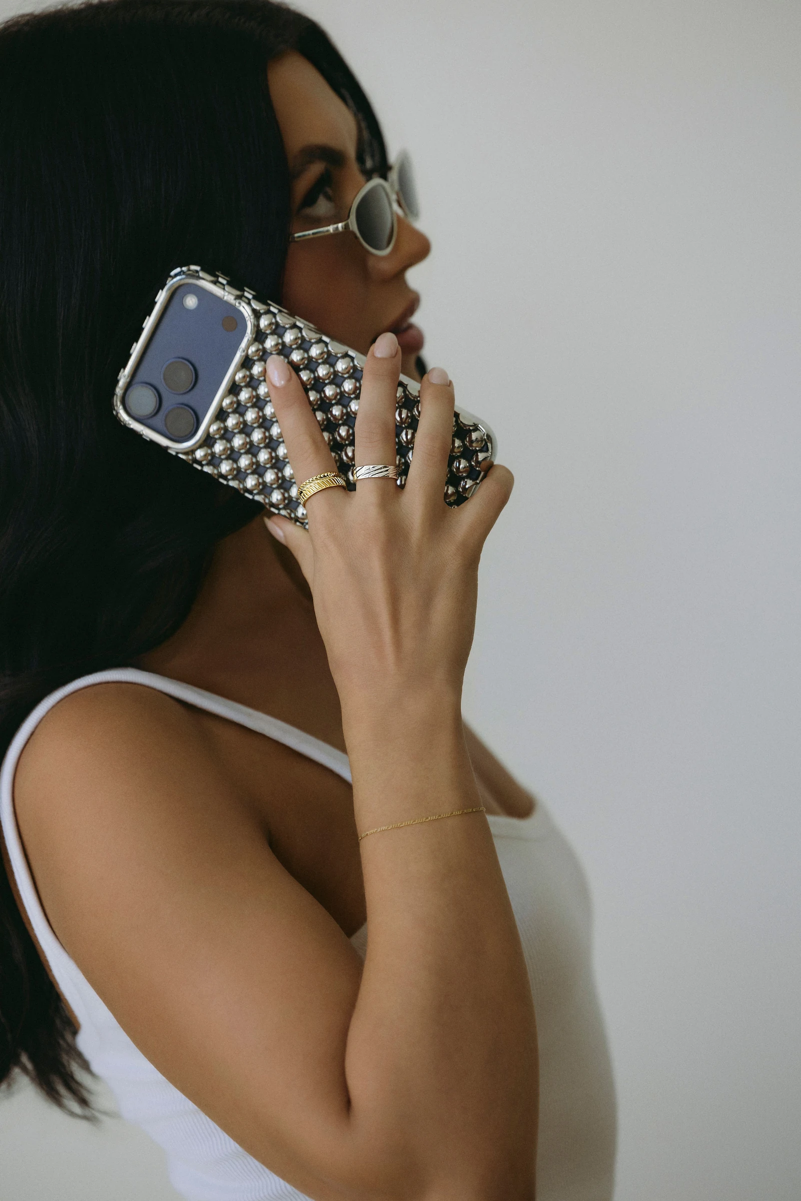 Model in sunglasses on a jeweled phone, wearing rings