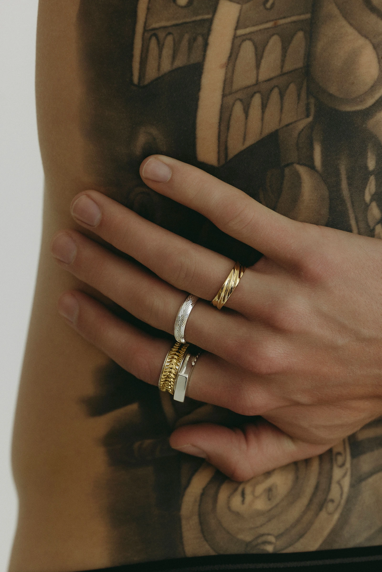 Close view of rings on a tattooed model’s hand